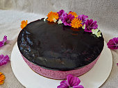 raspberry cake with blackberry jelly frosting. purple and pink colors of the corpus in the shape of a circle. decoration of meadow flowers. marigold and mallow in a bright orange composition