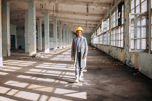 Portrait of female architect at the construction site in the building that needs renovation