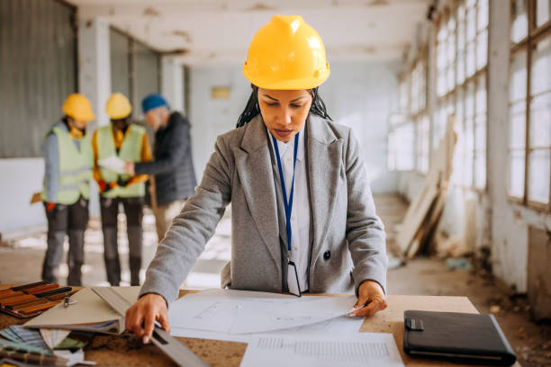 istock Female architect looking at the architectural project at the construction site 1992574510