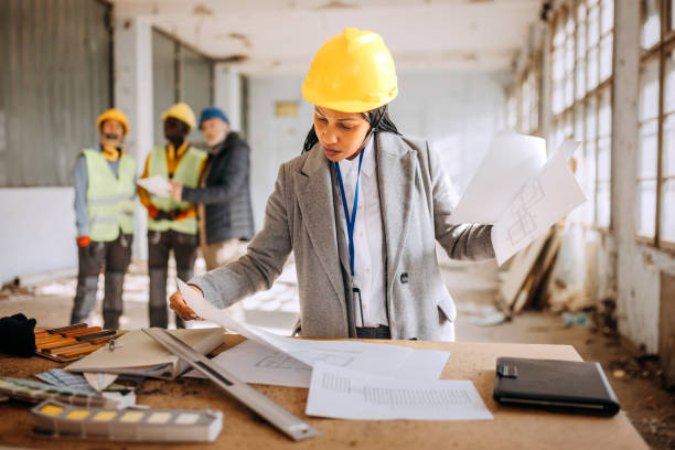 istock Female architect looking at the architectural project at the construction site 1992575580