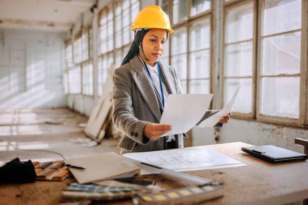 istock Female architect looking at the architectural project at the construction site 1992577248