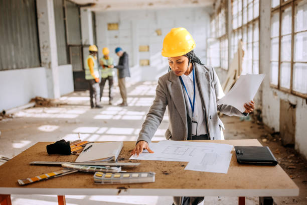 Female architect looking at the architectural project at the construction site