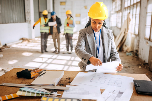 Female architect looking at the architectural project at the construction site