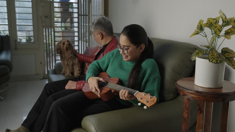 daughter playing guitar and senior father playing with Yorkshire Terrier