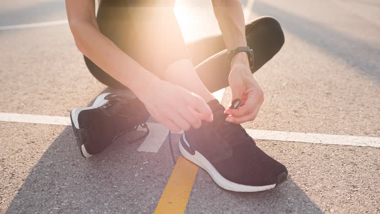 Young fitness woman tying shoelaces on sports shoe, getting ready for run