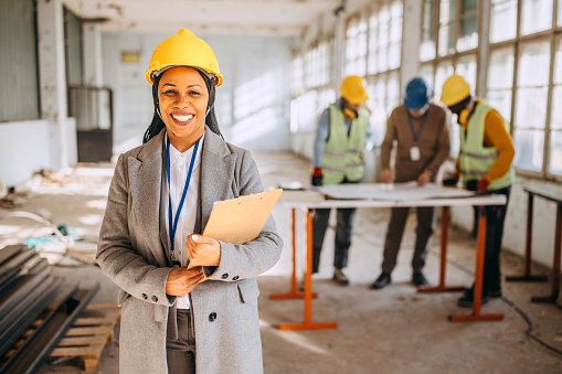 Portrait of female architect at the construction site in the building that needs renovation