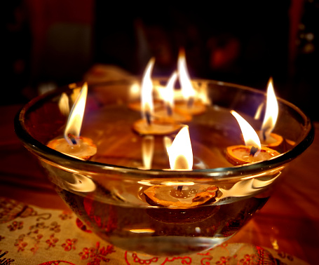 a traditional Christmas table with a metal tree and candles spins the merry-go-round with hot air. tinkling carillon. dropping a candle shell in a bowl of water is a tradition