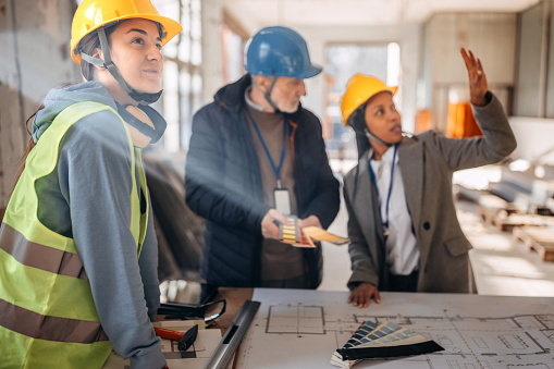 Architects looking at the architectural project and explaining to construction worker what to do