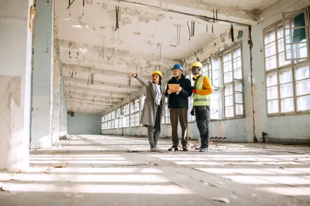 Architects looking at architectural project and explaining to construction worker