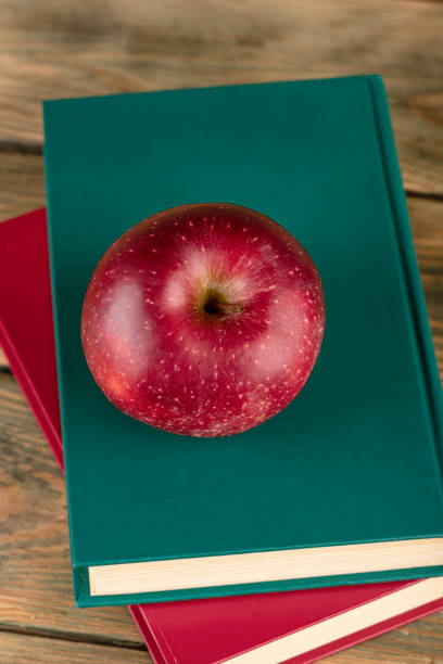 Top view of a red apple lying on hardcover books. Concept of knowledge.