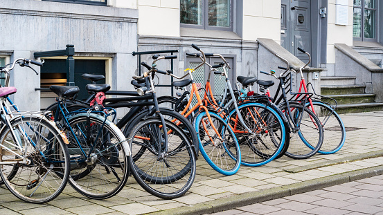 Bike parking in the city. Bicycle parking along a street near a city building in Amsterdam. An urban cityscape with bicycles. Walking bikes parked casually along an old street in Netherlands.