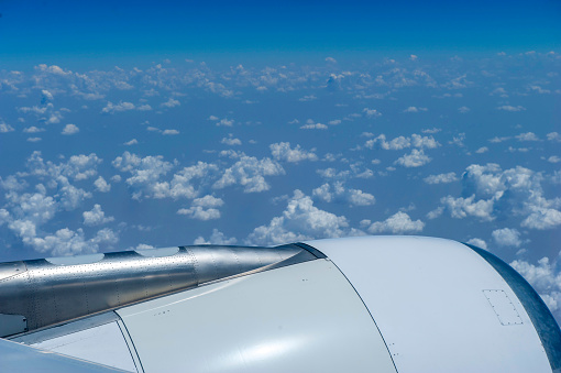 An overhead view of an airplane flying across a blue sky, leaving a white contrail behind it.