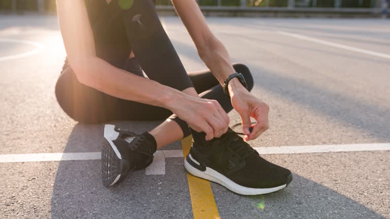 Fitness woman tying shoelaces and starts smartwatch app