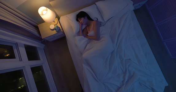 Top view asian woman sleep well at night on the bed in dark bedroom