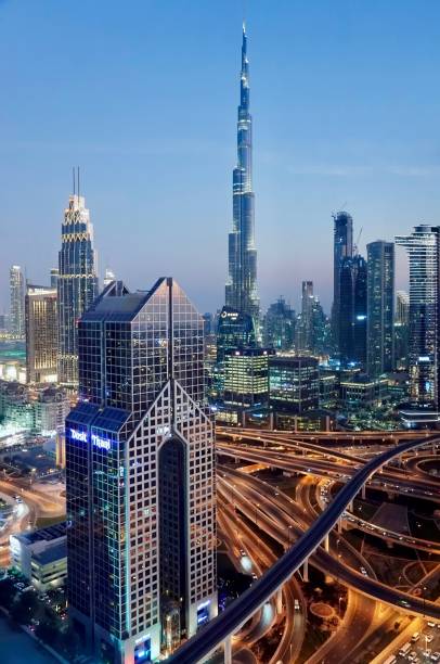 vista noturna de alto ângulo do dubai moderno, incluindo o dusit thani hotel em primeiro plano e o burj khalifa ao fundo, emirados árabes unidos. - middle east highway street night - fotografias e filmes do acervo