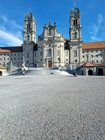 The Abbey of Einsiedeln is one of the most important baroque monastic sites and the largest place of pilgrimage in Switzerland. The image shows the building exterior with the two towers and the main entrance.