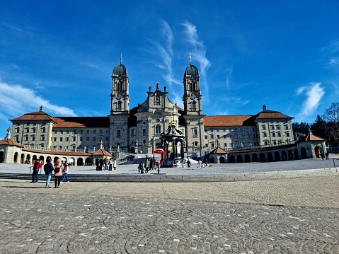 The Abbey of Einsiedeln is one of the most important baroque monastic sites and the largest place of pilgrimage in Switzerland. The image shows the building exterior with the two towers and the main entrance.
