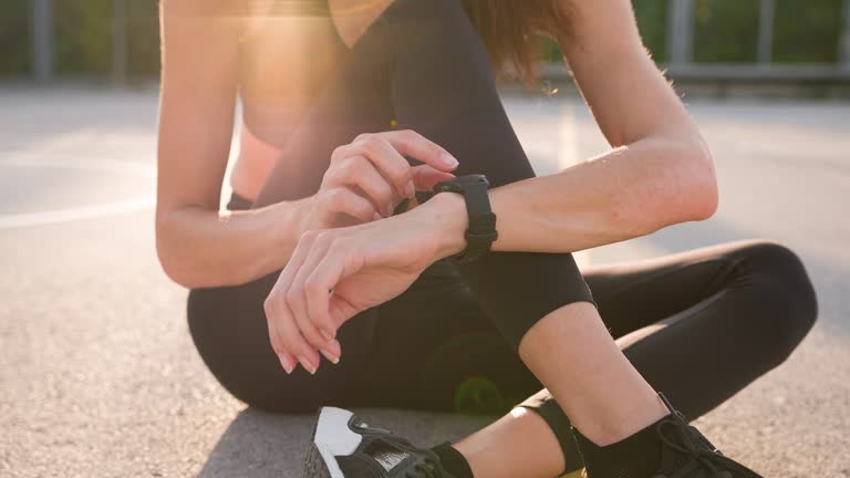 Fit woman preparing for exercise, tying shoelaces, starts smartwatch tracker
