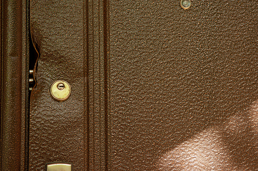 large durable lock is broken in a metal door close-up. Damaged door lock in a country house