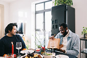 African man receiving a Christmas gift from friends during festive dinner