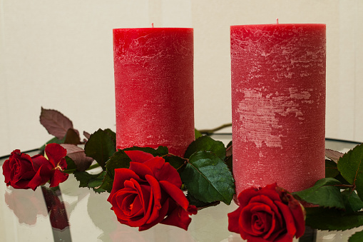 Red roses and candles on a glass table.