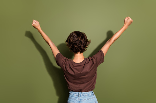 Back rear view photo of satisfied optimistic woman with short haircut raising fists up win lottery isolated on khaki color background.
