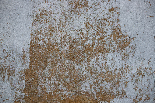 Layers of faded paint and the ravages of time tell a visual story on this urban wall. The image presents a palimpsest of colors and textures, with white splotches that suggest a canvas of human activity, weathering, and the passage of time.