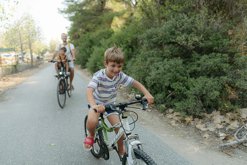 Photo of two young boys, enjoy beautiful summer morning riding bicycles by the sea