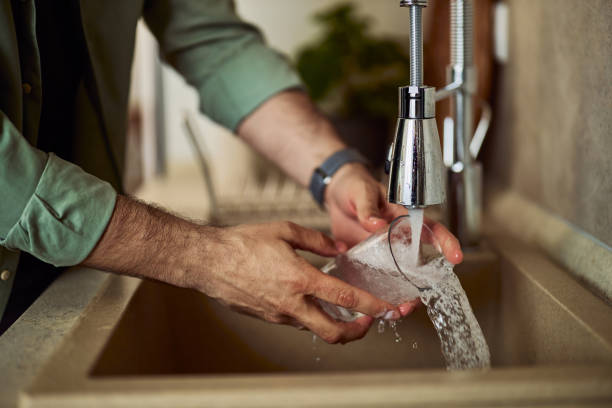 istock A man washing cup and rinse it with running water in the kitchen sink. 1992709358
