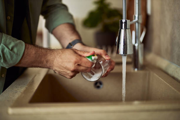 istock A close-up of a male's hands, washing a cup, using a detergent and a sponge. 1992709369