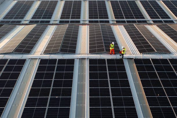 istock Aerial view of workers installing solar panels on a roof. 1992724422