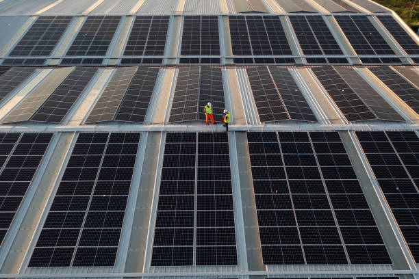 istock Aerial view of workers installing solar panels on a roof. 1992724441