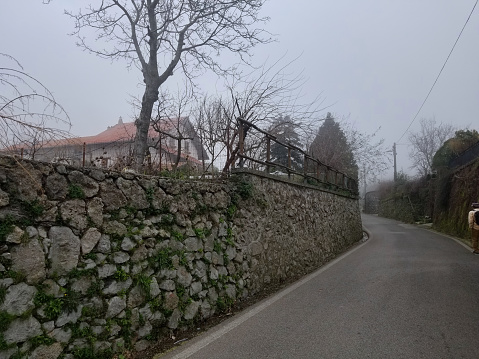 Empty rural road with stone wall and bare trees in Agerola, Amalfi Coast, Italy