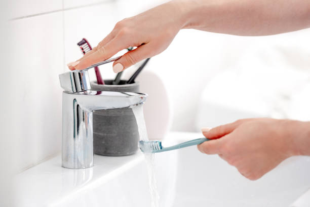 istock Girl'S Hand Holds Toothbrush Under Water Stream 1992748463