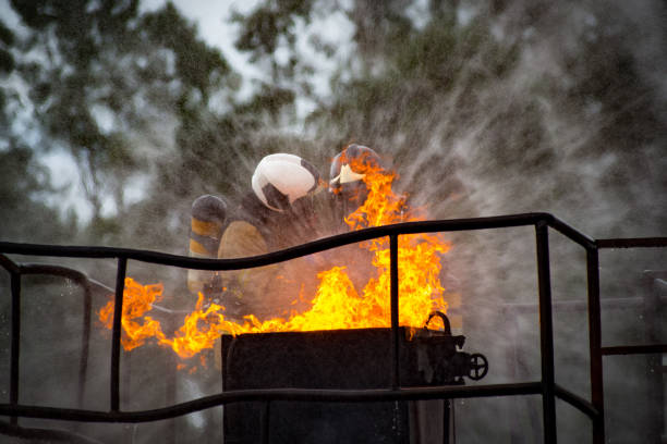 Front view of a couple of firefighters trying to extinguish a flame