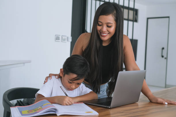 Indonesian Mother Watching Her Son Doing Homework.