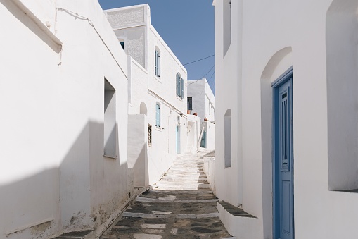 Cycladic alley with white blue houses with blue windows and doors under clear sky on Sifnos island, Cyclades, Greece