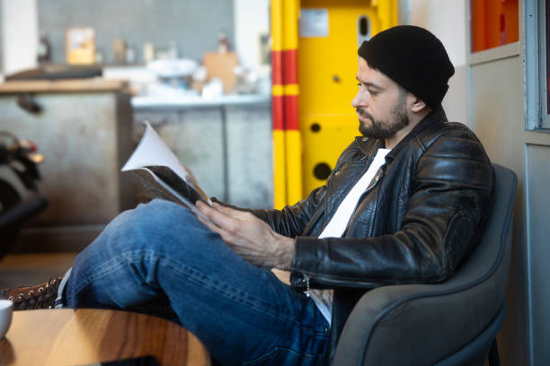 Young man sitting carefree reading a magazine\nCopyspace mockup on table