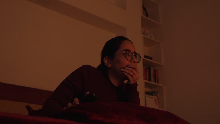 Young woman at home in living room watching movie scary horror movie