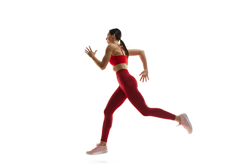 Dynamics, endurance and energy. Female runner athlete in motion, running, training against white studio background. Concept of sport, active and healthy lifestyle, sportswear, competition
