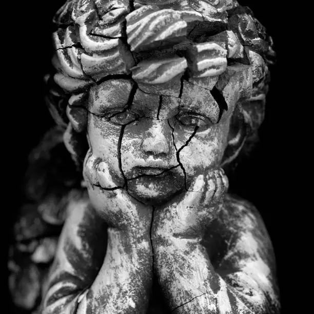 Old and cracked statue of Cherub little child