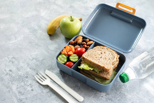 istock School lunch box with sandwich, vegetables, fruit and water on table, healthy eating concept. 1992808357