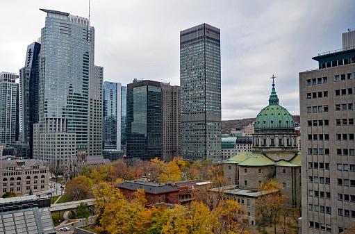 Montreal, QC, Canada, Nov. 11, 2023: Modern office towers stand near the historic, domed Mary, Queen of the World Cathedral in downtown Montreal.