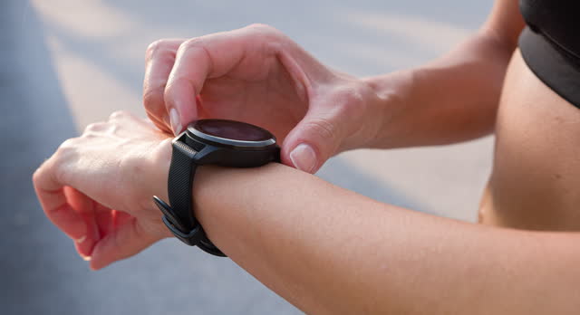 Woman setting and checking smart watch on a race track before running
