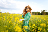 Beautiful woman walking in the blooming field at sunny summer day.