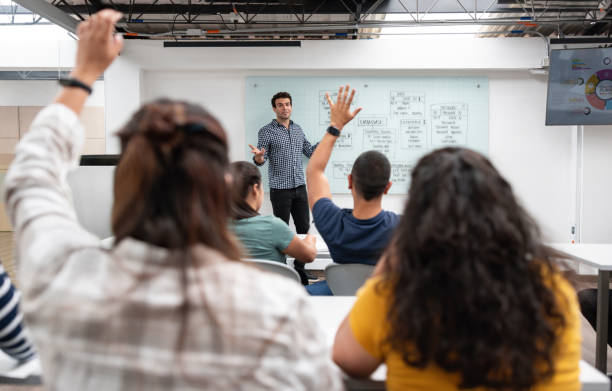 Students asking question to the teacher in an IT class Group of students raising their hand and asking question to the teacher in an IT class - education concepts male teacher white board stock pictures, royalty-free photos & images
