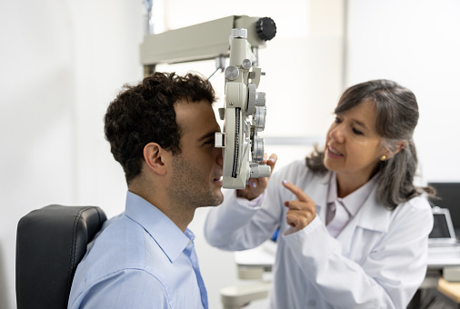 Female ophthalmic doctor diagnosing elderly patient`s sight using ophthalmic equipment