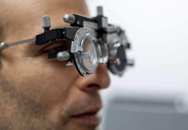 Close-up on a Latin American man getting an eye exam at the optometrist and looking through a phoropter