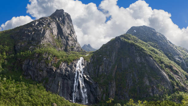 istock Sunlight dapples a majestic Norwegian waterfall Valefossen cascading down rugged cliffs, surrounded by lush greenery and dramatic peaks. Lofoten Island 1992852714