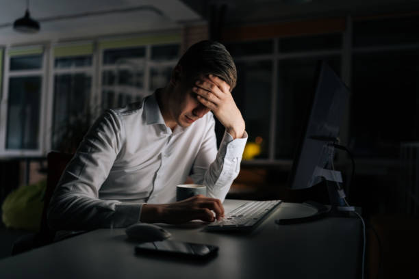 Exhausted businessman working in evening office alone. Tired anxious manager losing failure working on computer at late night. Tired worried business man at workplace in office holding head on hands. hombre de negocios agotado que trabaja solo en la oficina de la noche. gerente cansado y ansioso que pierde el fracaso trabajando en la computadora a altas horas de la noche. hombre de negocios cansado y preocupado en el lugar de trabajo